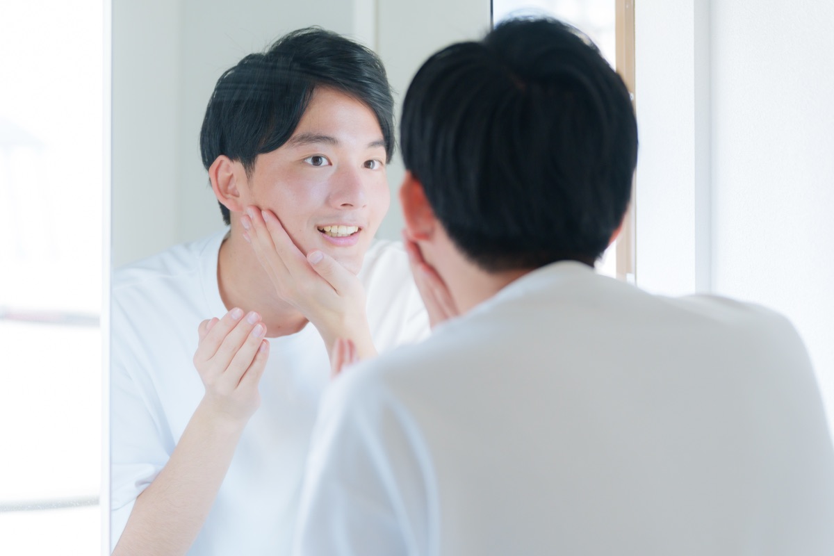 鏡の前で身だしなみを整える就活生の男性