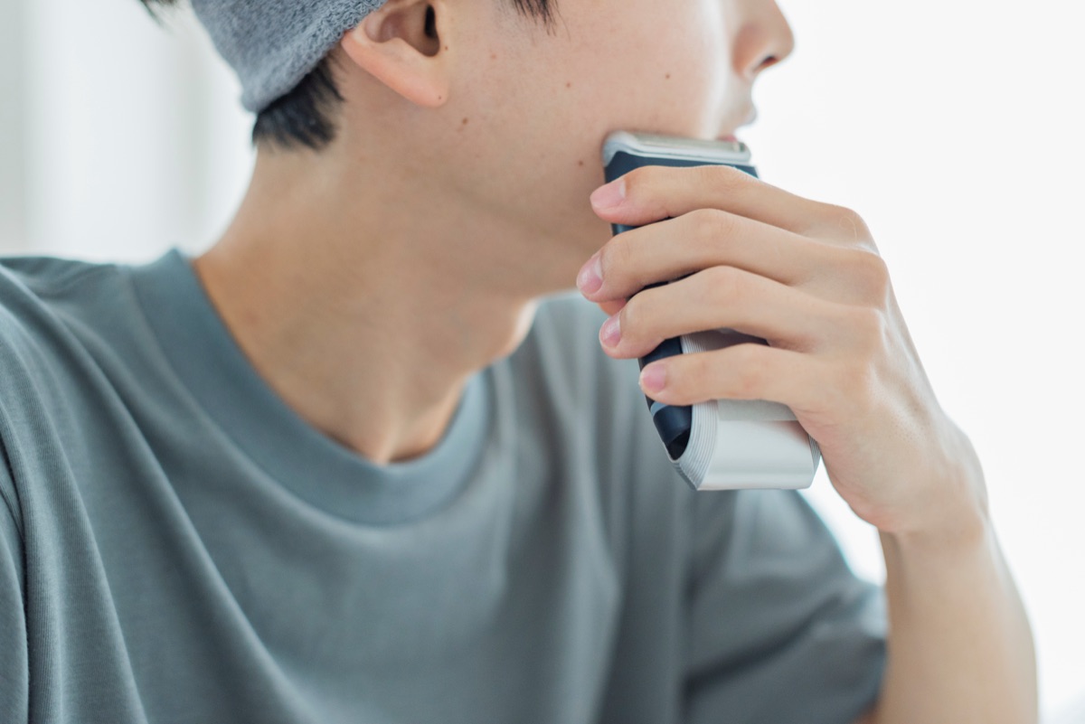 電気シェーバーで髭を剃る男性